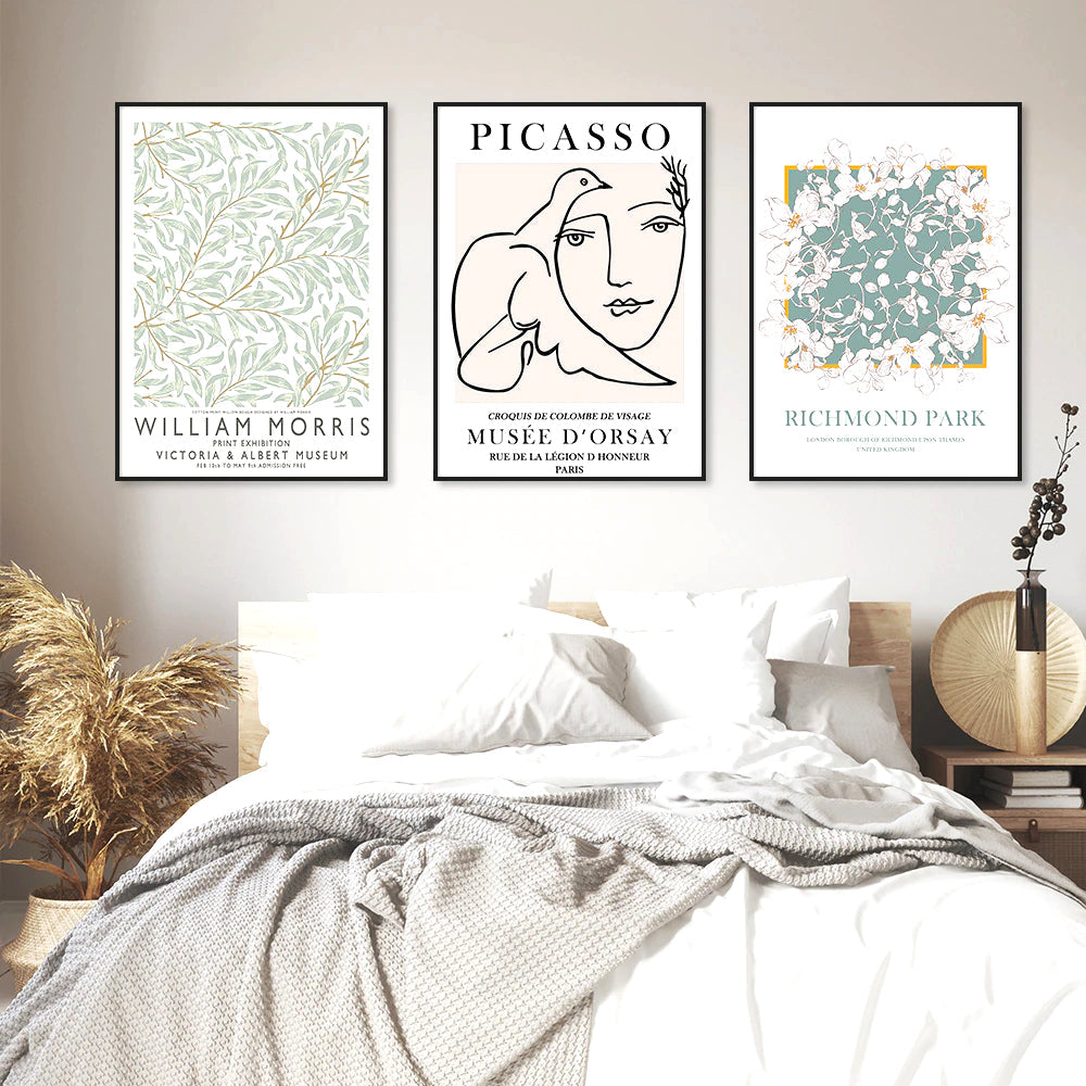Three framed art prints above a bed.