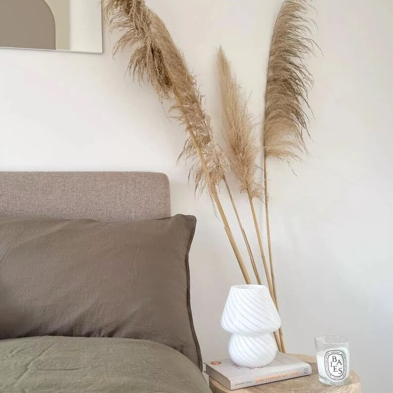Bedroom decor with pampas grass, mushroom lamp, and candle.