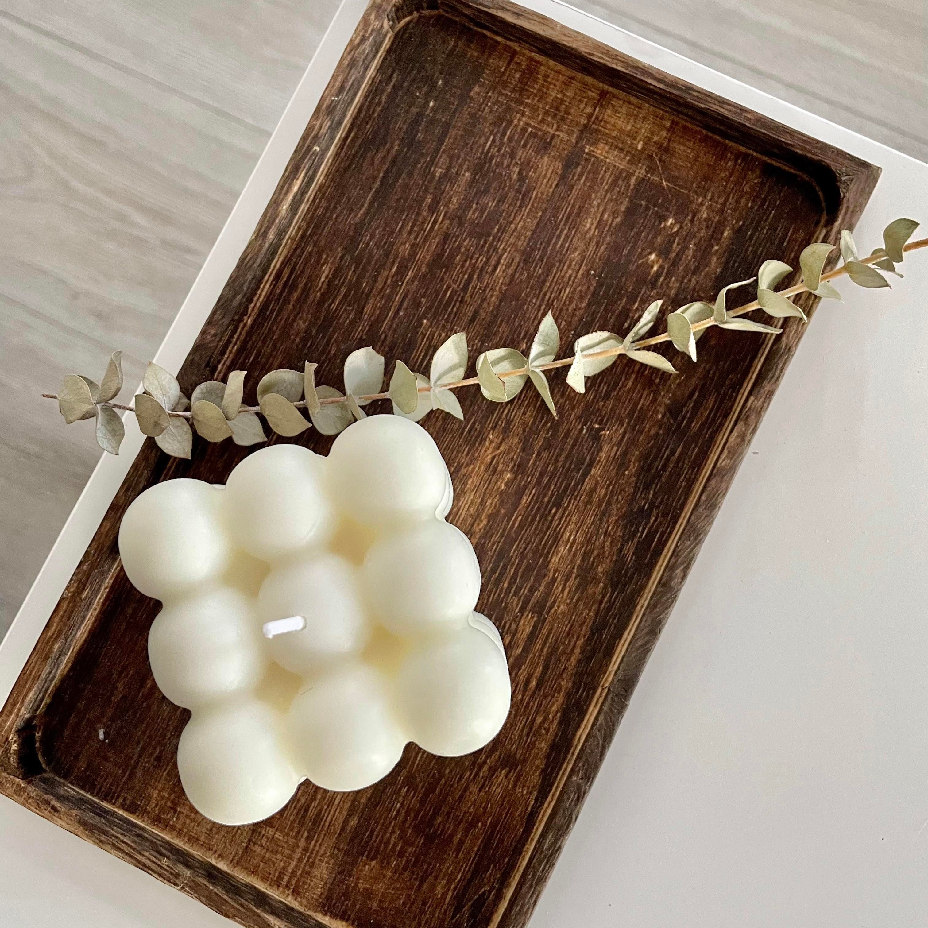 Bubble candle on a wooden tray with greenery.