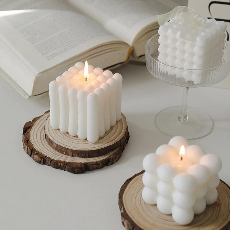 White bubble candles with lit flames on wood coasters