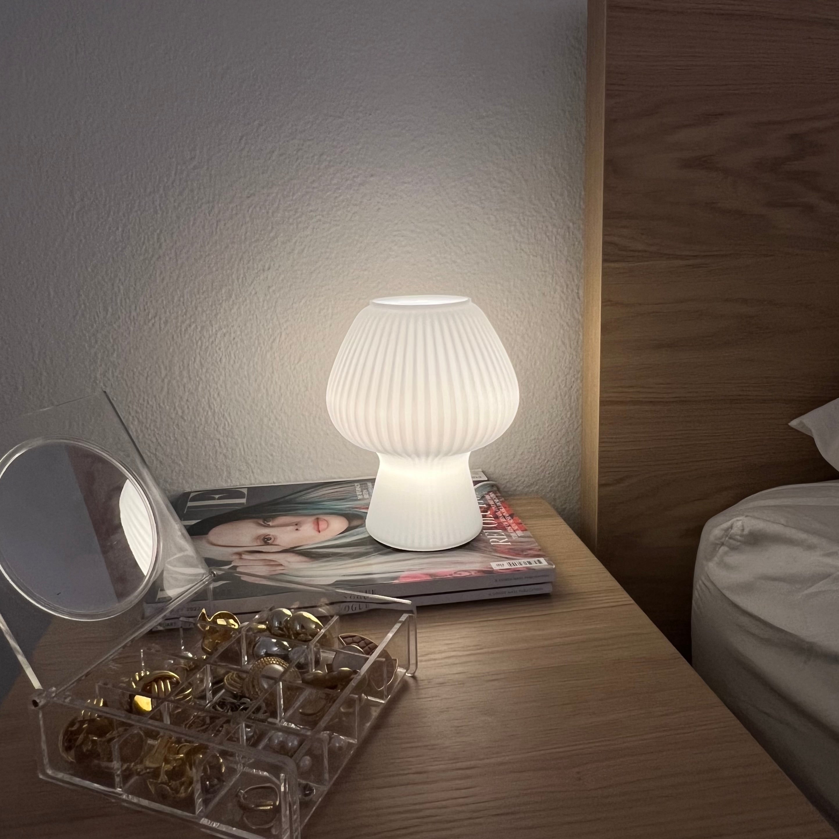 Mushroom-shaped lamp on a nightstand with a magazine and jewelry.